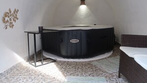 A hot tub in a room with a tiled floor, a wicker chair, and a wall-mounted decoration. - Müllers Wellness Ferienhaus (Döbrököz)