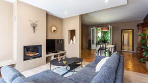 Un salon moderne doté d’une cheminée, d’un téléviseur, d’un coin repas et offrant une vue sur l’extérieur.
