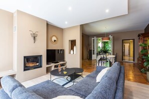 Een moderne woonkamer met een open haard, een televisie, een eethoek en uitzicht op de omgeving.