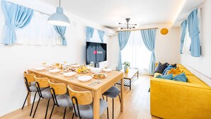 Un'area pranzo moderna con un tavolo in legno, sedie e uno schermo televisivo.