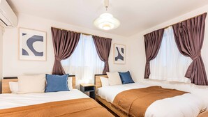Una camera d'albergo con due letti, un comodino e una lampada a soffitto.