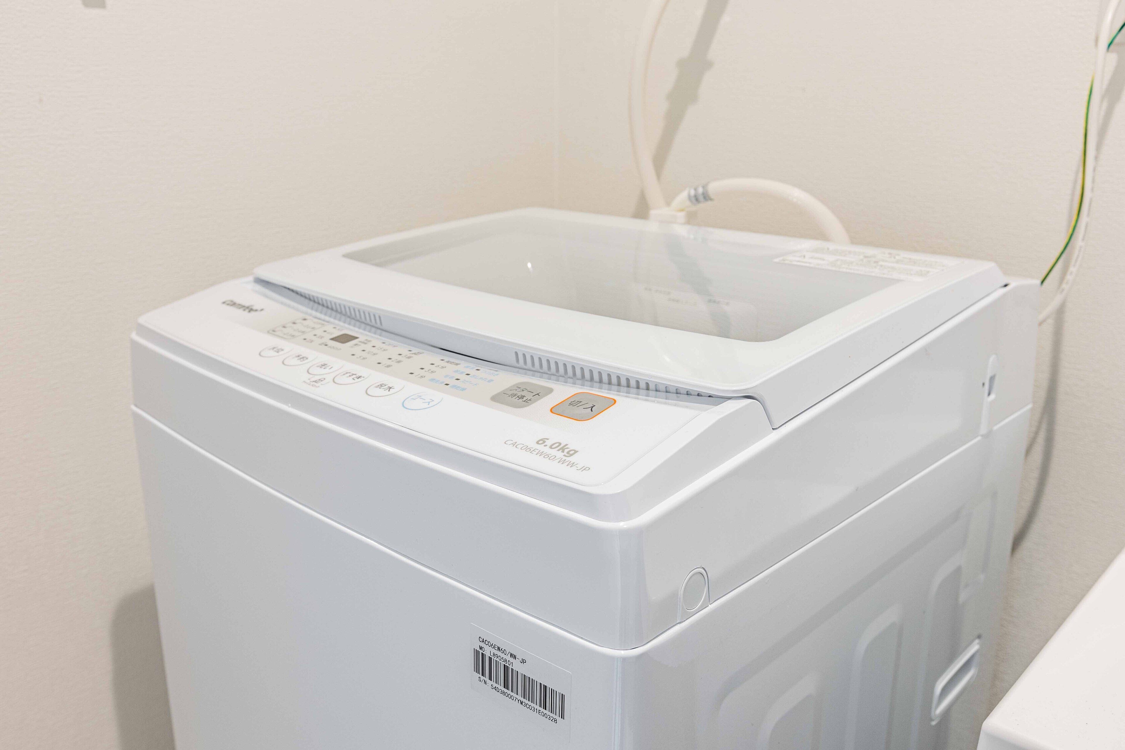Eine Frontansicht einer weißen Waschmaschine mit Bedienfeld, einem transparenten Wassertank und einem eingesteckten Stromkabel.