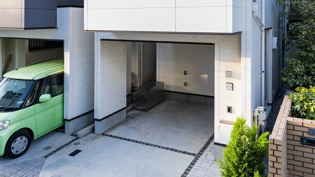 Un edificio moderno a due piani con tetto piatto, ampie finestre e un garage visibile.