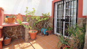 A tiled patio with terracotta pots, a hose reel, and a window with black bars. - 1020 Casa Pat (Nerja)