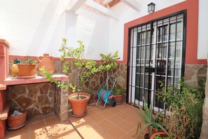 A tiled patio with terracotta pots, a hose reel, and a window with black bars. - 1020 Casa Pat (Nerja)