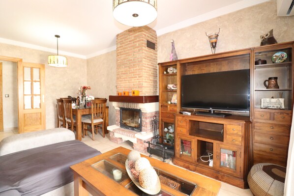 A living room with a fireplace, television, and wooden furniture. - 1020 Casa Pat (Nerja)