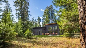 Une maison moderne entourée de grands arbres.