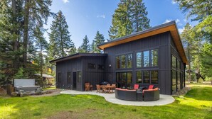 Une maison moderne dotée d’une grande terrasse, entourée d’une forêt.