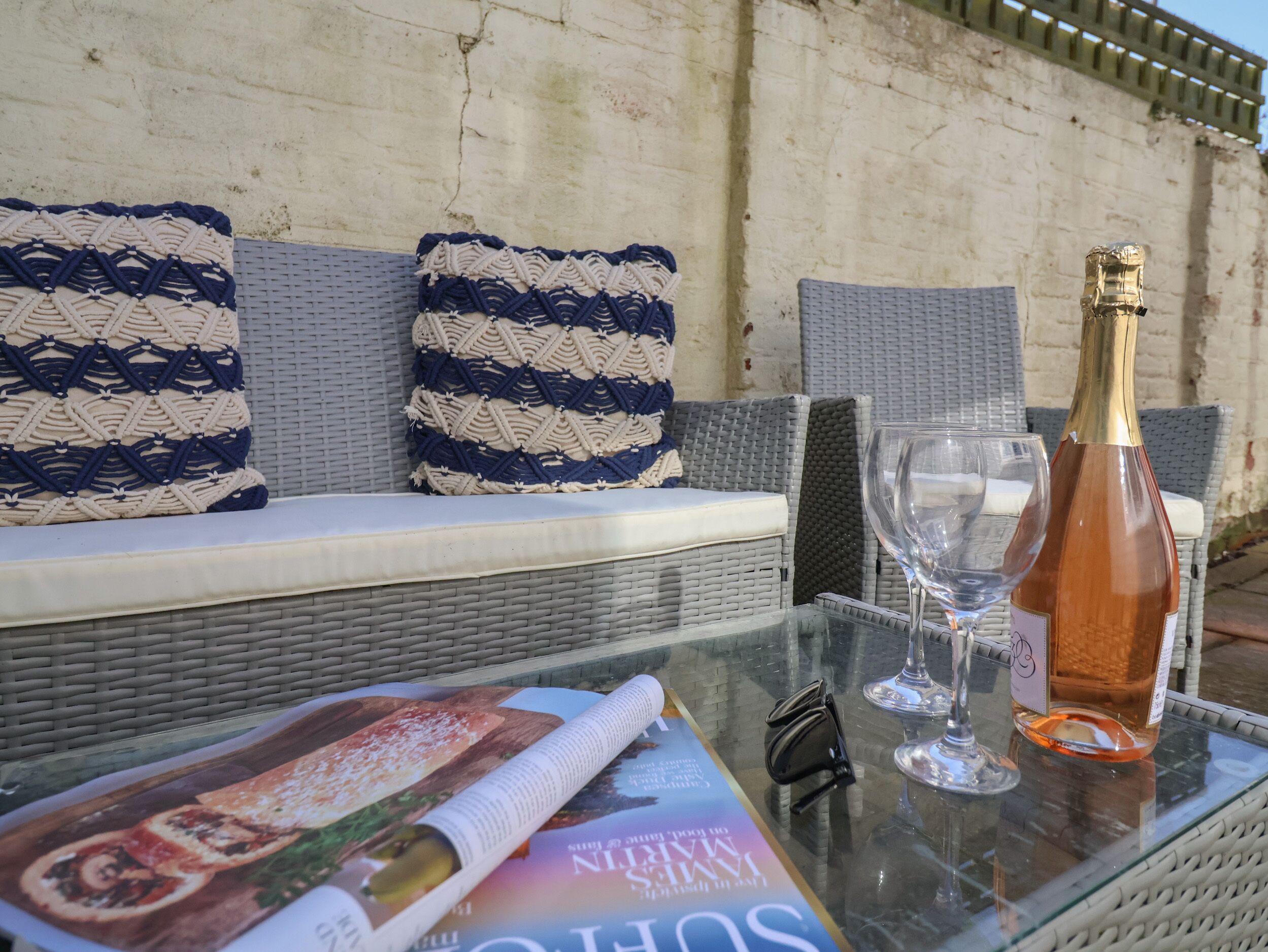 A glass table with a magazine, a wine glass, and a bottle of wine.