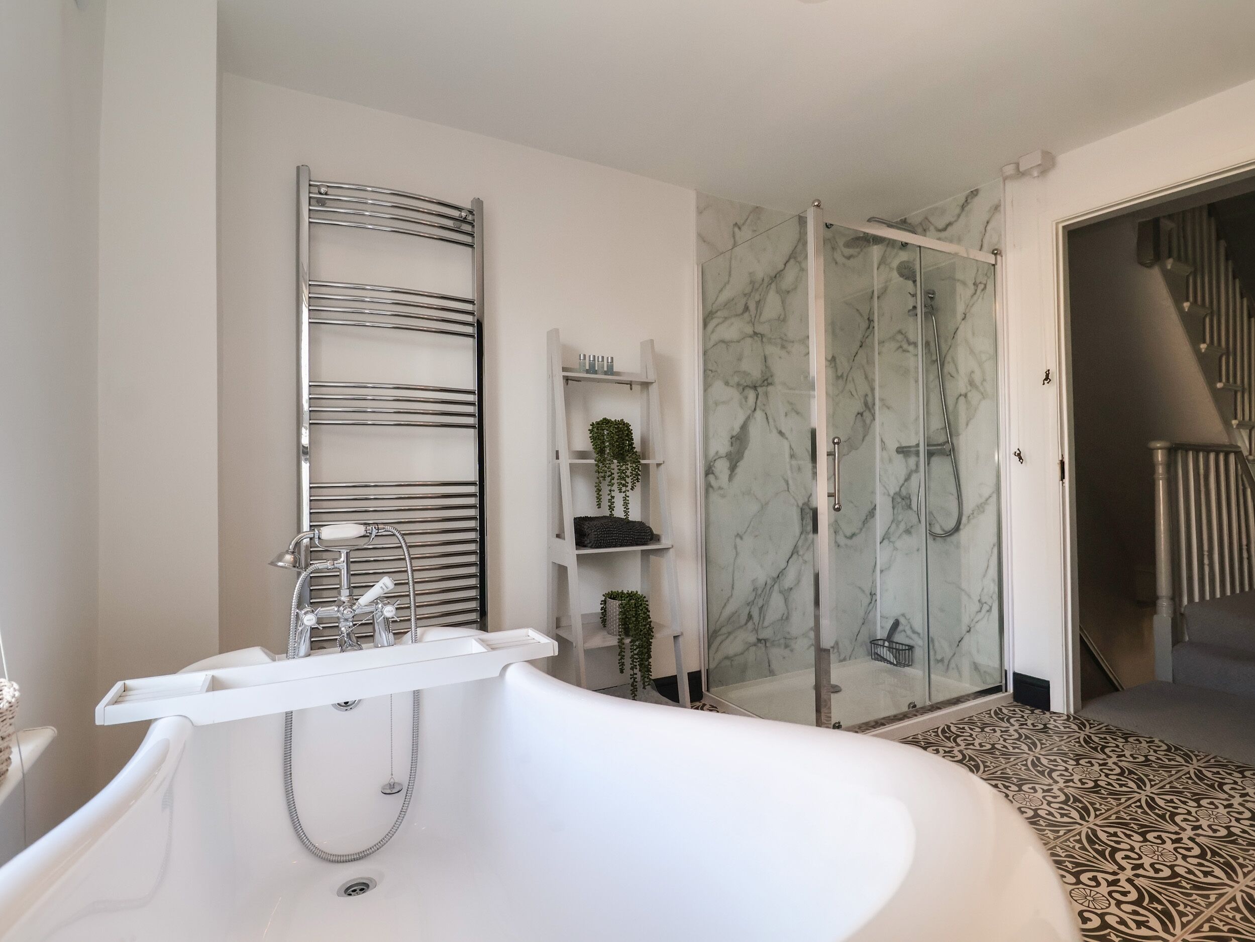 A modern bathroom with a freestanding bathtub, a glass-enclosed shower, and marble walls.