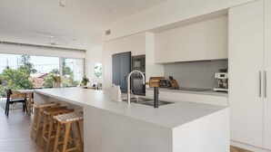A modern kitchen with a large island, bar stools, and a view of the outdoors.