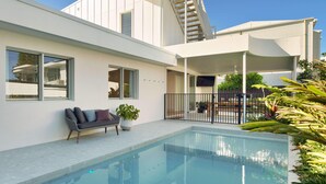 A modern house with a swimming pool, a balcony with a white railing, and a staircase leading to an upper level.