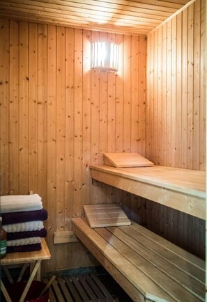 A sauna room with wooden walls and benches. - 3 Bed House - Sleeps 5 - Sauna - Garden - Gym (Kingston Upon Thames)