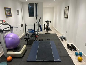 A home gym with exercise equipment, a treadmill, and various weights.