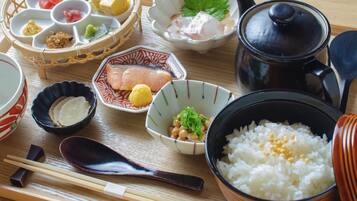 A traditional Japanese meal setup with various dishes, including rice, fish, and pickled vegetables, arranged on a wooden table.