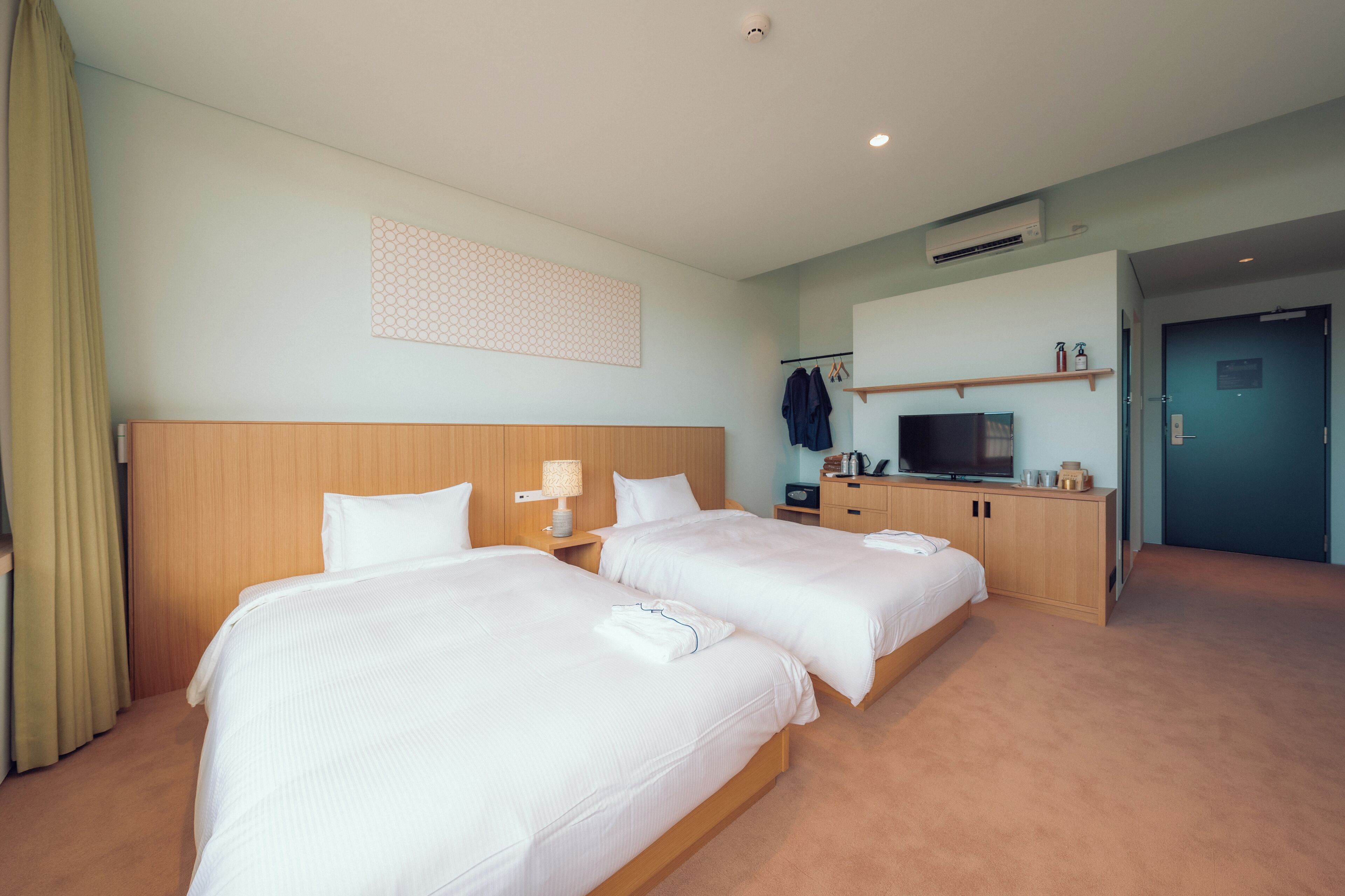 A hotel room with two beds, a TV, a desk, and a wardrobe.