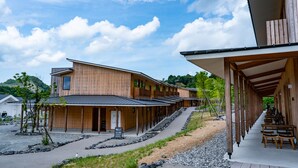 A modern wooden building with multiple rooms, a covered outdoor seating area, and a gravel pathway. - Hatago VISON (Taki)
