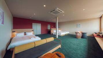 Quarto de hotel com uma cama grande, um sofá, uma mesa pequena e uma cadeira. Há duas camas no quarto.