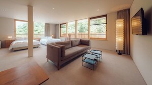 A modern hotel room with a large bed, a sofa, two small tables, and a TV mounted on the wall. - Hatago VISON (Taki)