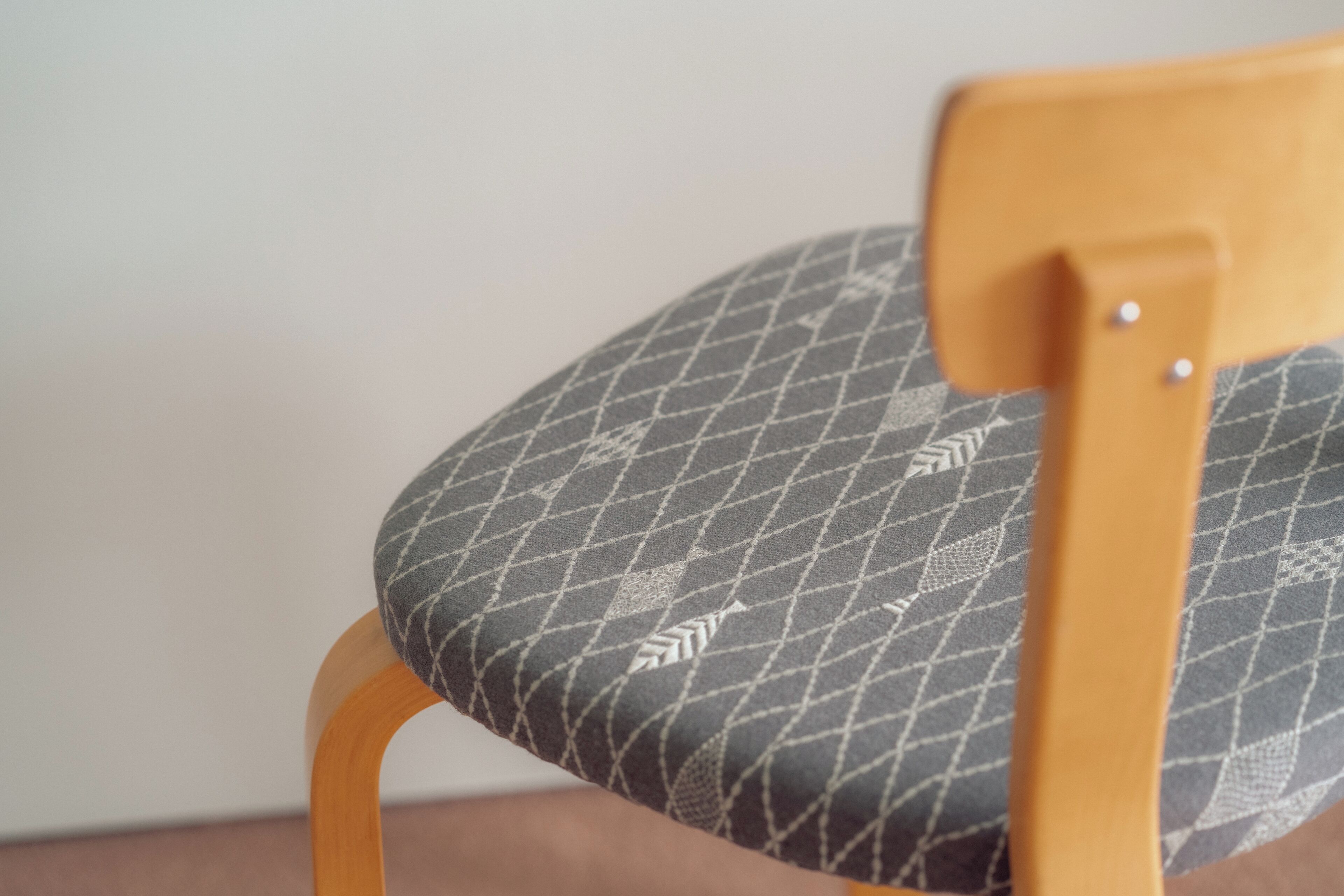 A close-up of a chair with a patterned cushion and wooden frame.
