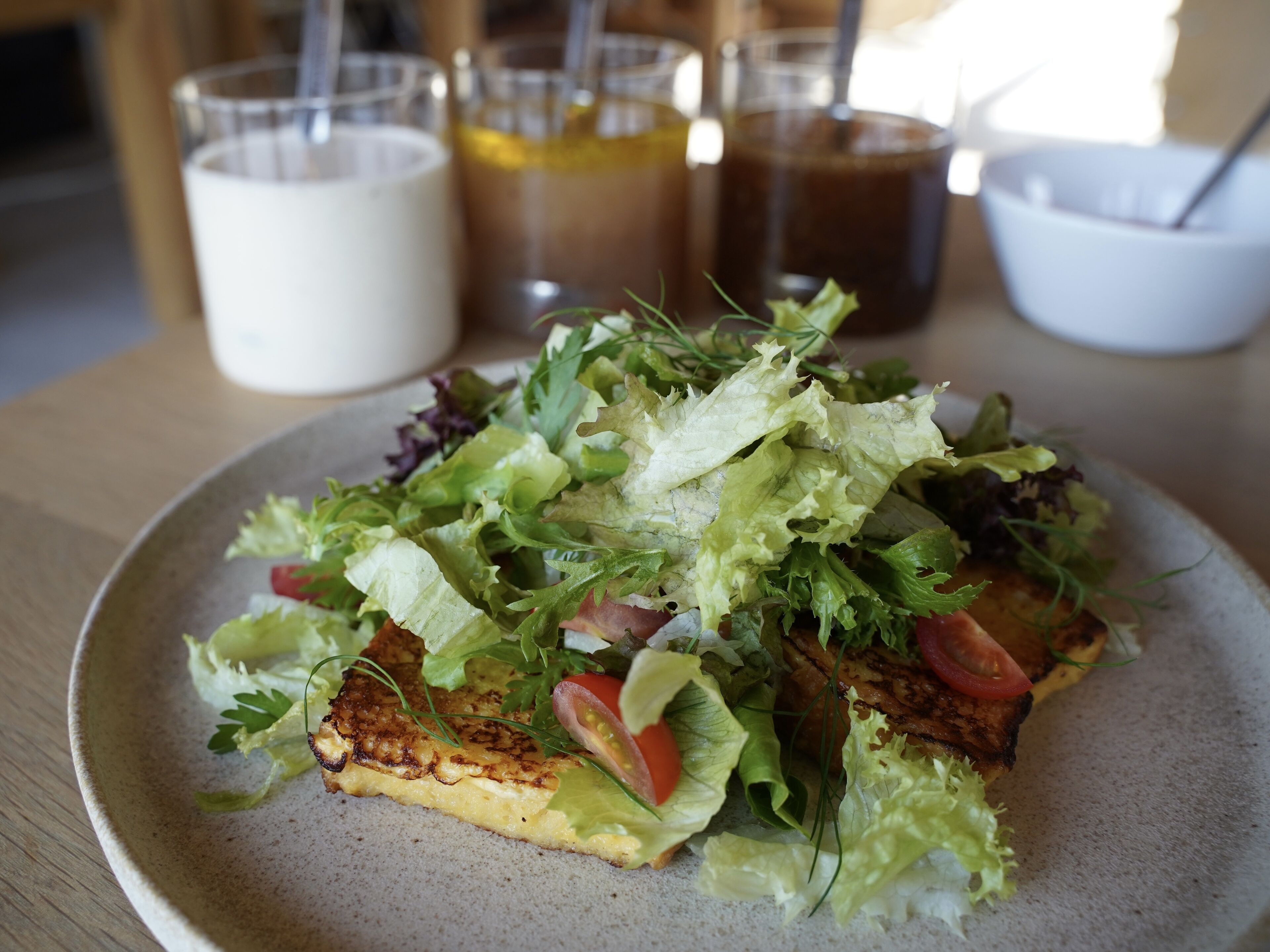 A plate of food with a salad and grilled meat, accompanied by drinks and a bowl.