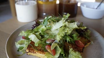 A plate of food with a salad and grilled meat, accompanied by drinks and a bowl.