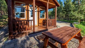 Uma cabana de madeira com varanda, uma mesa e cadeiras.