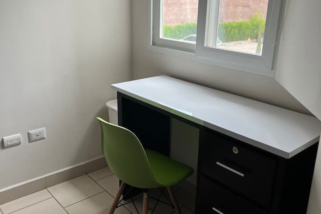 A small, private office with a desk and chair, a window, and a tiled floor.