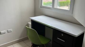 A small, private office with a desk and chair, a window, and a tiled floor.