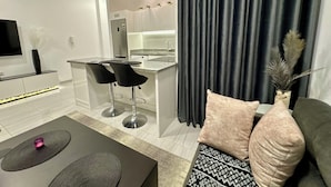 A modern kitchen with a built-in stove, two bar stools, and a dining area with a black table and a decorative vase.
