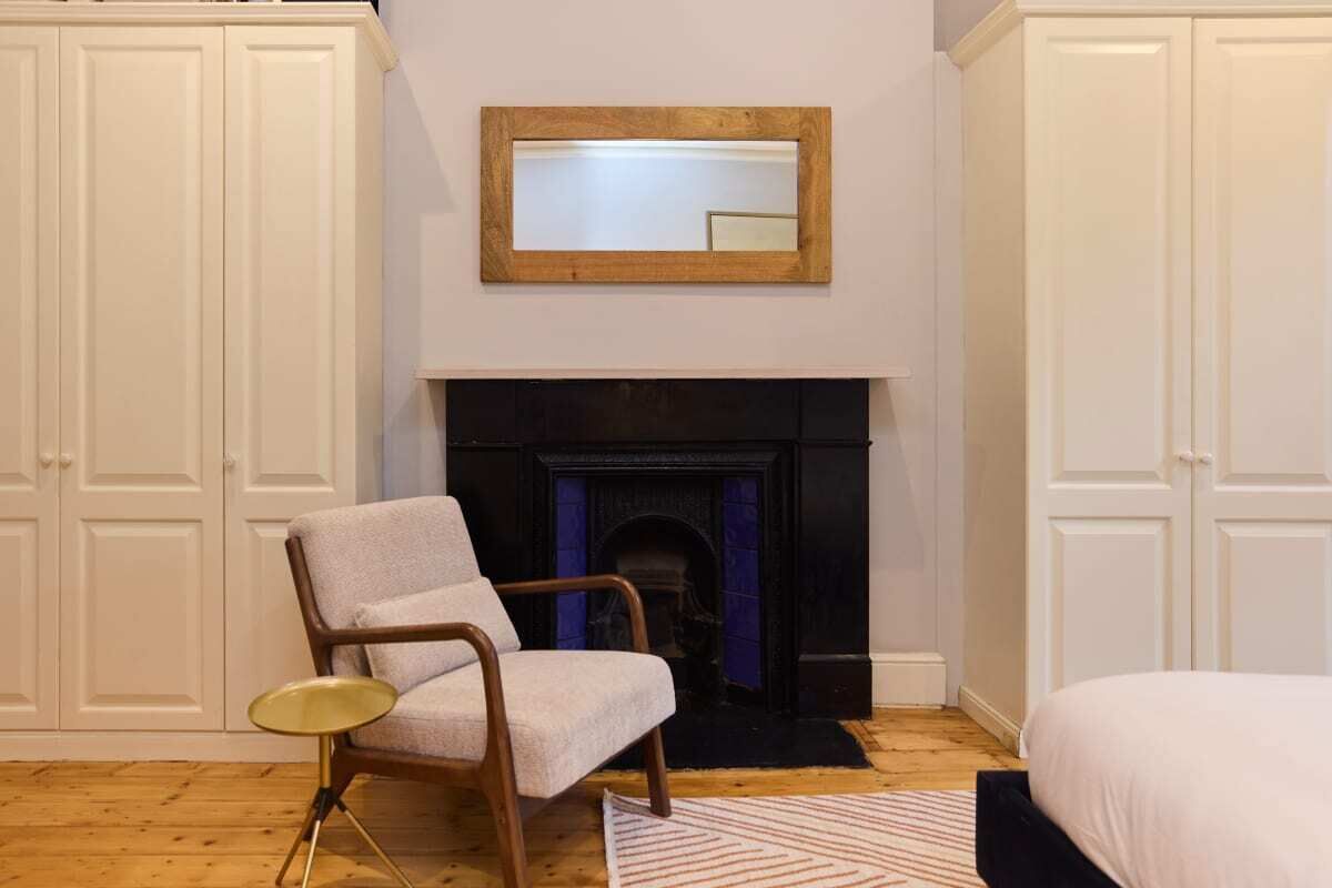 A room with a fireplace, a chair, and a bed.