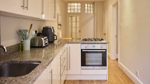 A kitchen with white cabinets, a granite countertop, a stove, and a toaster.