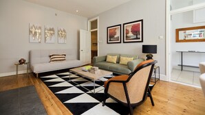 A living room with a sofa, a chair, a coffee table, and artwork on the walls.