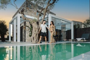 Une villa moderne dotée d’une piscine, d’une architecture en pierre et d’une structure en forme de pergola.