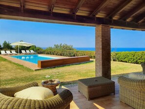 A covered outdoor area with a pool, lounge chairs, and wicker furniture. - 3734 Villa Villacolle by Barbarhouse (San Costanzo)