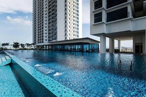 Una piscina con acqua cristallina, circondata da edifici moderni.