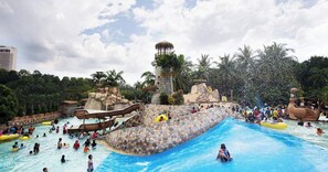 Un parque acuático con una piscina grande, toboganes y una estructura tipo torre.