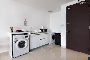 A compact kitchen with a washing machine, a microwave, and a sink. - Lovely Studio Trefoil Near Setia City Mall & SCCC (Shah Alam)