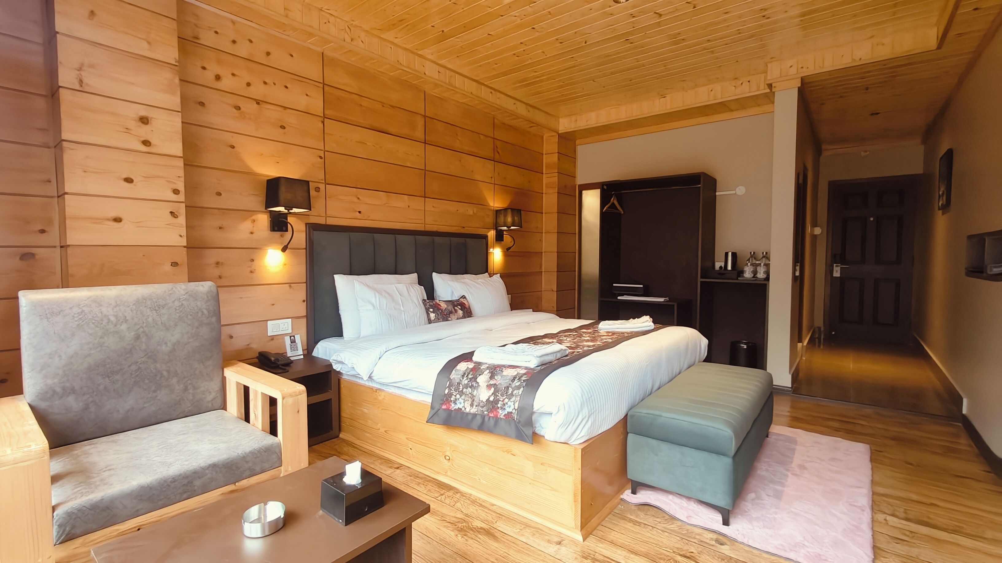 A wooden cabin-style bedroom with a bed, bedside tables, a chair, and a bench.