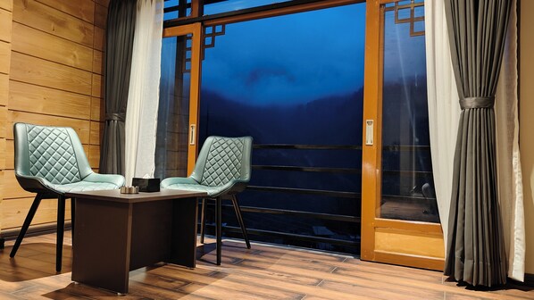 A room with two chairs, a table, and a view through a glass door.