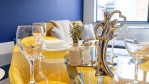 Une table dressée avec des verres à vin, un salière et un poivrier, et un objet décoratif en argent en forme de cœur.