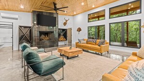 Una sala de estar moderna con chimenea, ventanas amplias y un ventilador de techo.