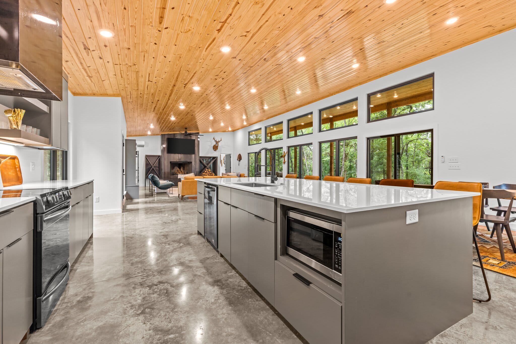 A modern kitchen with a large island, stainless steel appliances, and a wooden ceiling.