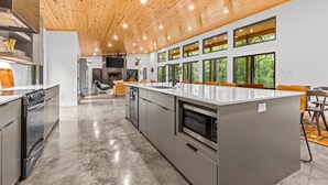 Una cocina moderna con una isla grande, electrodomésticos de acero inoxidable y techo de madera.