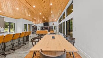 A spacious room with a long wooden table, multiple chairs, and a fireplace.