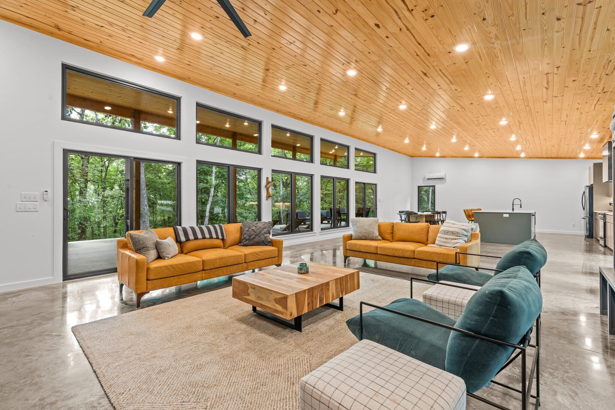 A spacious living area with large windows, wooden ceiling, and modern furniture.