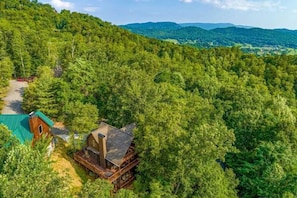 Escape to a secluded cabin surrounded by a lush forest, with a balcony offering a vantage point to enjoy the natural beauty.