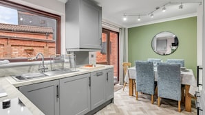 Une cuisine moderne avec des meubles gris, un évier en acier inoxydable et un sol à motifs en chevrons.
