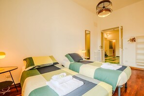 A hotel room with two beds, a desk, a chair, a lamp, and a mirror. - Candia Cento Apartment Vatican Museums (Rome)