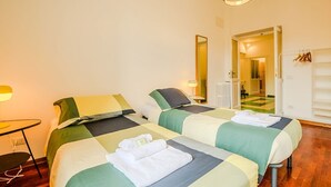 Ein Hotelzimmer mit zwei Betten, einem Schreibtisch, einem Stuhl, einer Lampe und einem Spiegel.